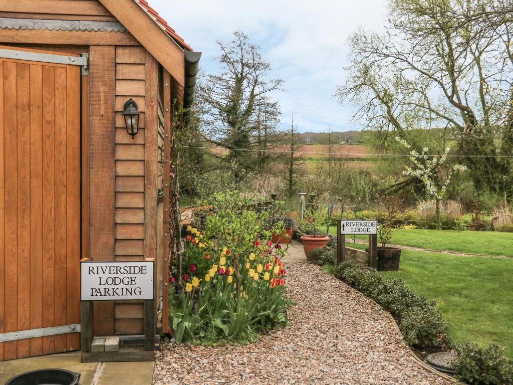 een tuin met een bord waarop staat dat een mysterieus huis verhuurd wordt bij Riverside Lodge in Norton