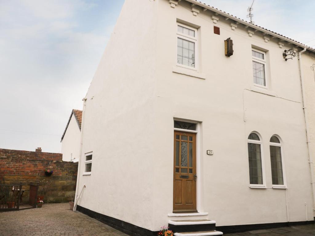 a white building with a wooden door on it at Sands End Cottage in Redcar