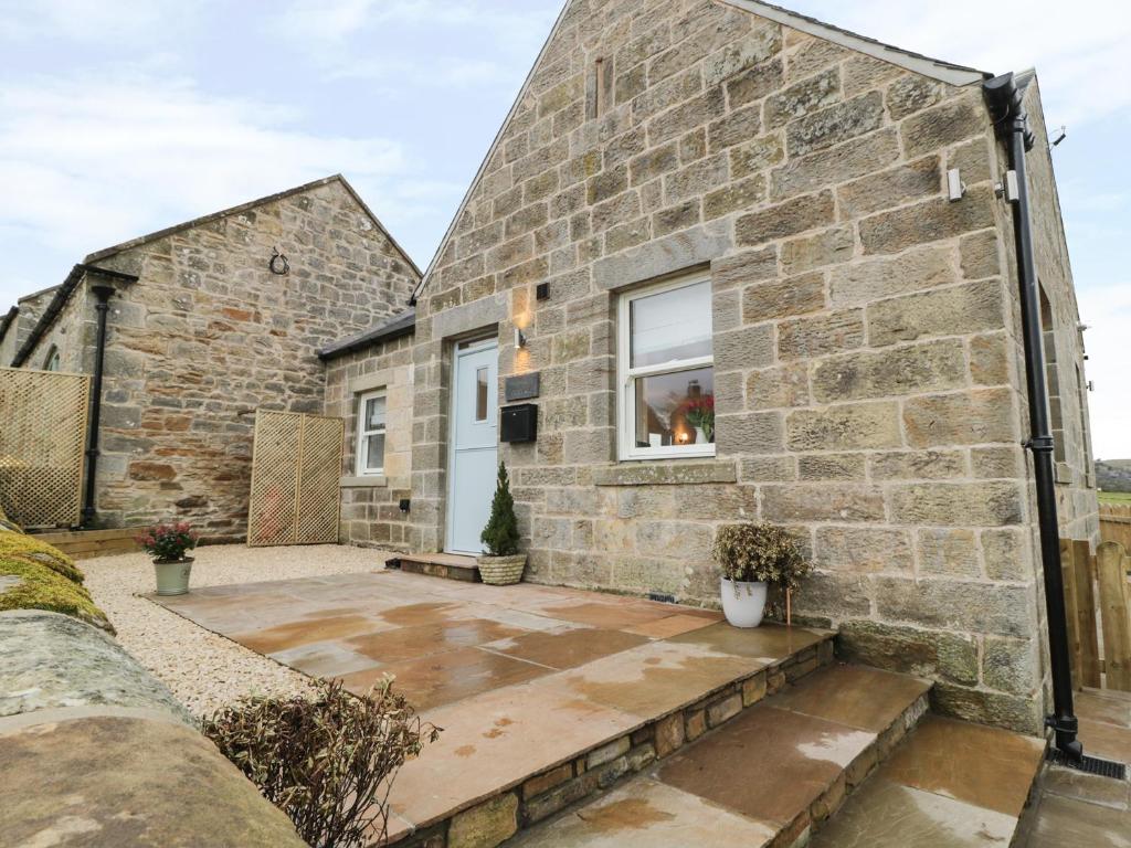 a stone house with a courtyard in front of it at Shepherds Cottage in Rothbury