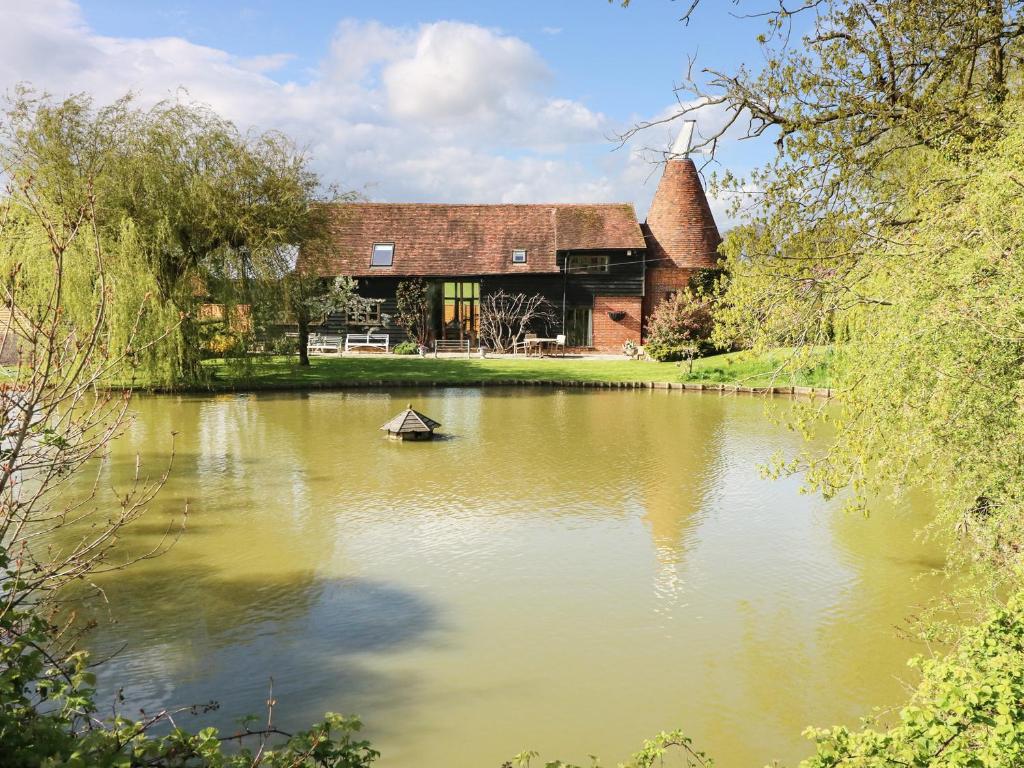 a house with a boat in the middle of a lake at Harbourne Oast in Tenterden