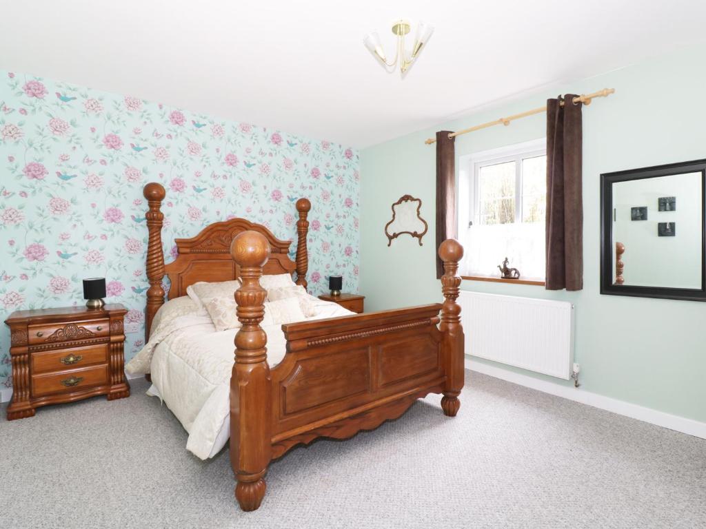 a bedroom with a wooden bed and a window at The Lodge in Brandon