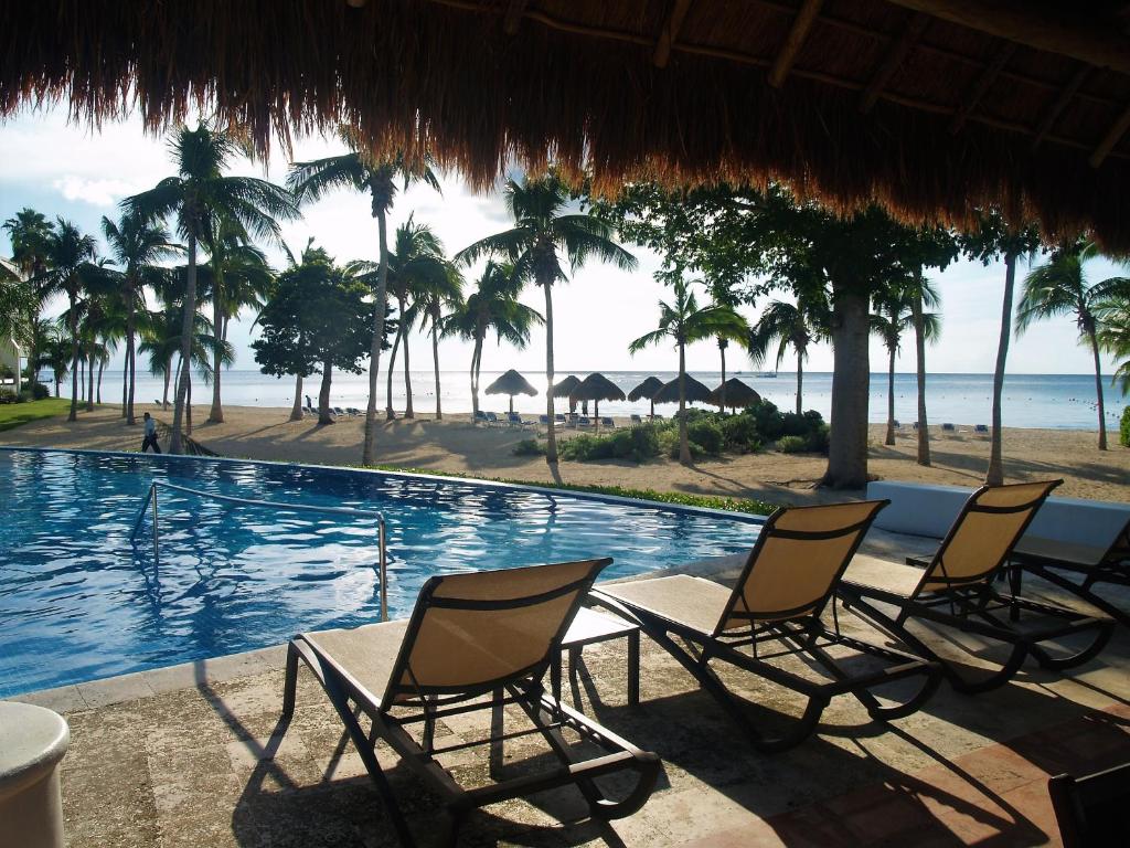 科蘇梅爾的住宿－Beachfront Apartment Your Home in Cozumel，一组椅子坐在游泳池旁
