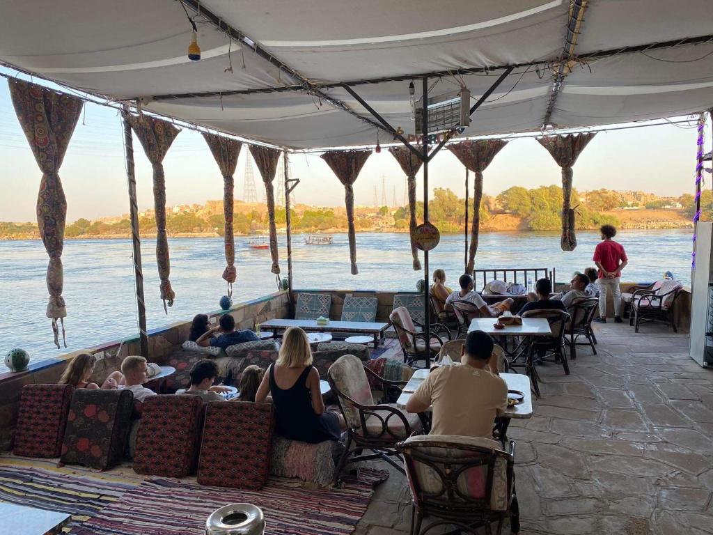 un gruppo di persone seduti ai tavoli vicino all'acqua di Opal privat nubian hotel a Aswan