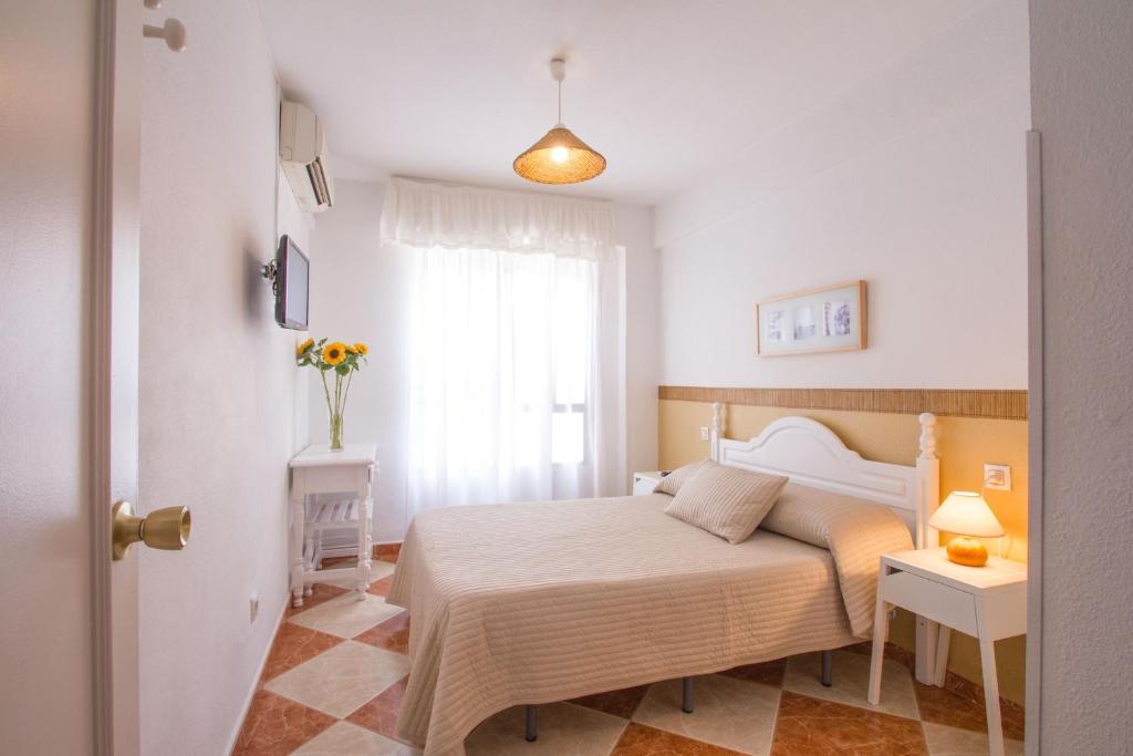 a white bedroom with a bed and a window at Hostal Jomarijo in Fuengirola