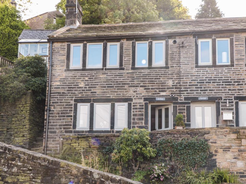 an old brick house with white windows at Bramble Cottage in Holmfirth