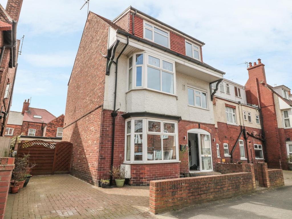 an old brick house with white windows on a street at Mayfield Sands in Bridlington