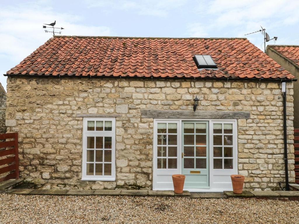 a stone house with white doors and a red roof at The Bothy, 21 West Street in Malton