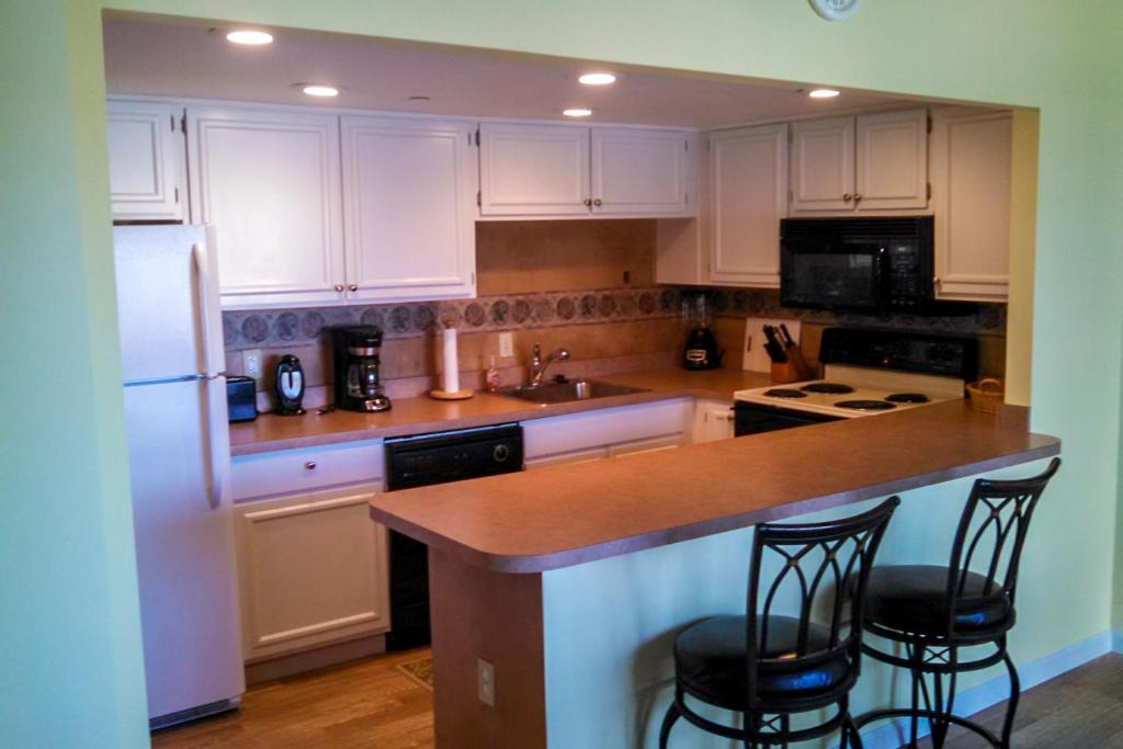 a kitchen with white cabinets and a island with bar stools at 9400 Bldg #203 in Ocean City