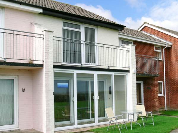 a house with a balcony and a table and chairs at Seascope in Kessingland