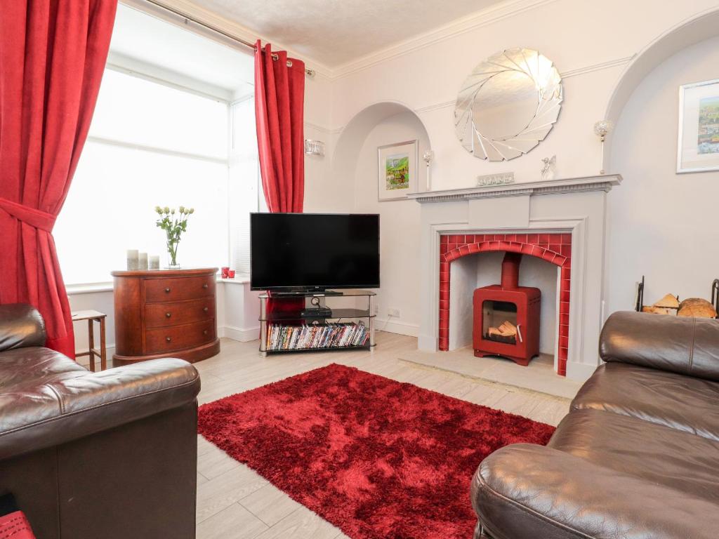 ein Wohnzimmer mit einem TV und einem Kamin in der Unterkunft Angel Cottage in Skipton