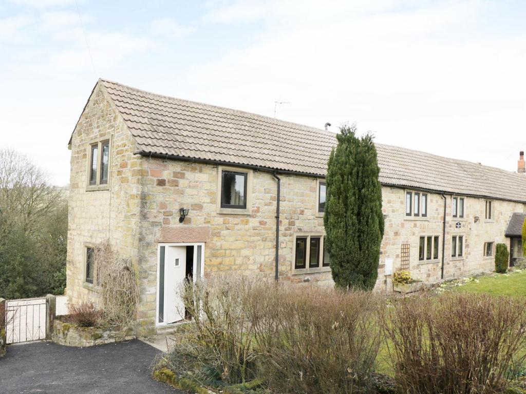 an old stone house with a white door at Woodlands Farm in Ashbourne