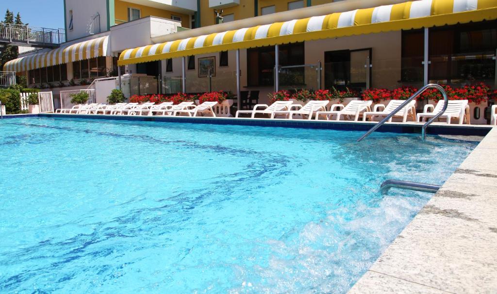 a large swimming pool with chairs and a hotel at Park Hotel Perù ***S in Lido di Jesolo