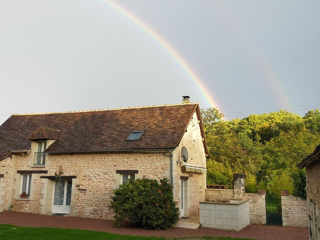 a rainbow in the sky above a stone house at Gite du Prieure in Vaux-sur-Vienne