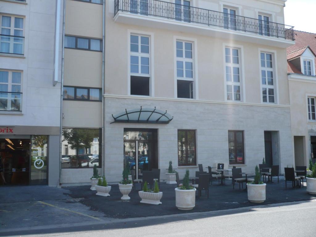 un bâtiment avec des tables et des chaises devant lui dans l'établissement Résidence d'Artagnan, à Montargis