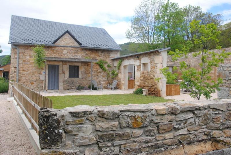 a stone house with a stone wall in front of it at Gîte Auberoques Aveyron- maison indépendante- classée 3 étoiles in Les Fonds