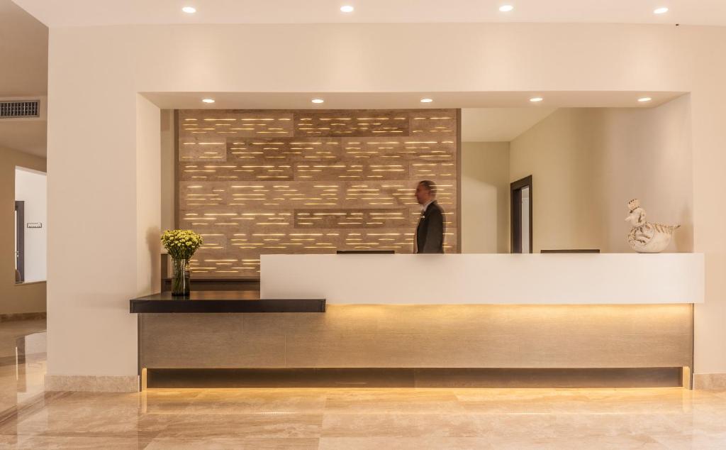 a man standing behind a reception desk in a lobby at Cala Cuncheddi - VRetreats in Murta Maria