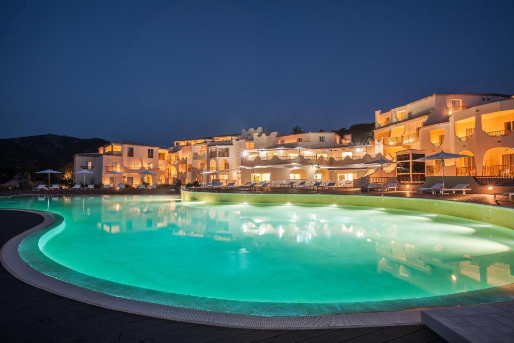 a large swimming pool in front of buildings at night at Cala Cuncheddi - VRetreats in Murta Maria