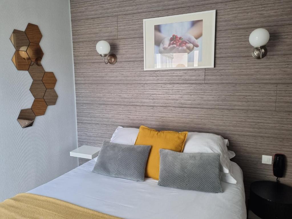 a bedroom with a bed with yellow and grey pillows at Hotel De L'Europe in Perros-Guirec