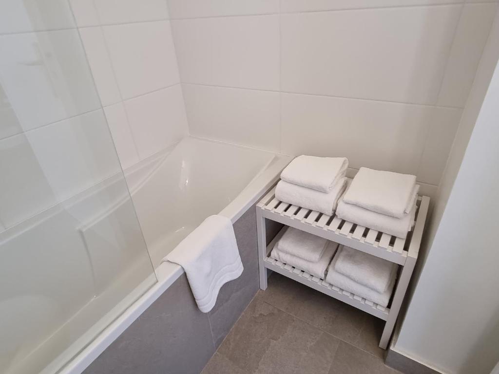 a white bathroom with a bath tub and towels at Hotel De L'Europe in Perros-Guirec