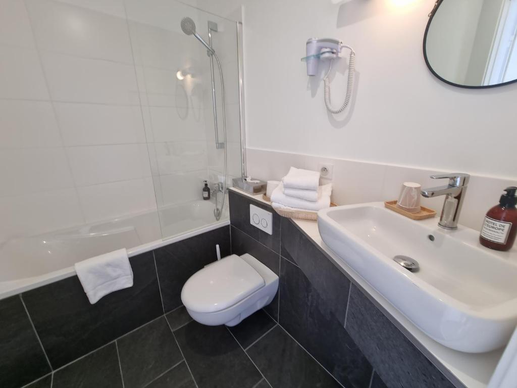 a white bathroom with a sink and a toilet at Hotel De L'Europe in Perros-Guirec