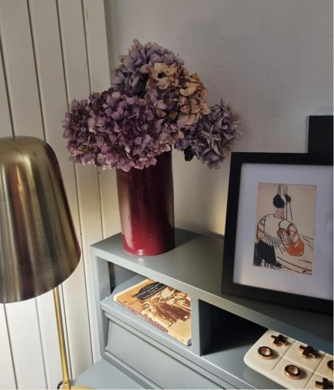 a vase with purple flowers on a shelf with a picture at Hotel De L'Europe in Perros-Guirec