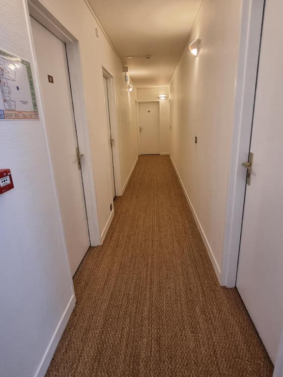 an empty hallway with a long corridor with white walls at Hotel De L'Europe in Perros-Guirec