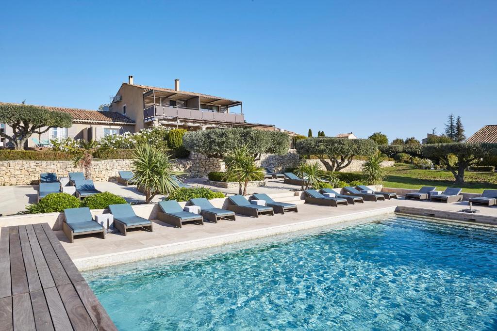 a hotel room with a swimming pool and lawn chairs at La Bastide Saint Georges & Spa in Forcalquier