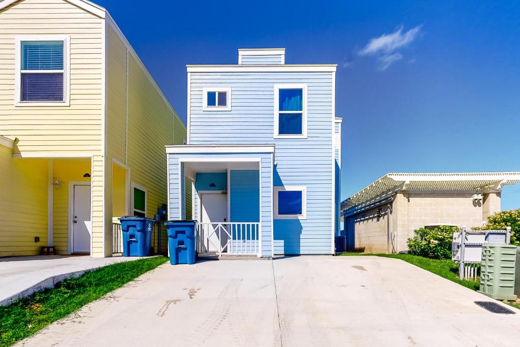 a white house with blue doors on a street at Las Joyas Bayview Home #202 in Port Isabel