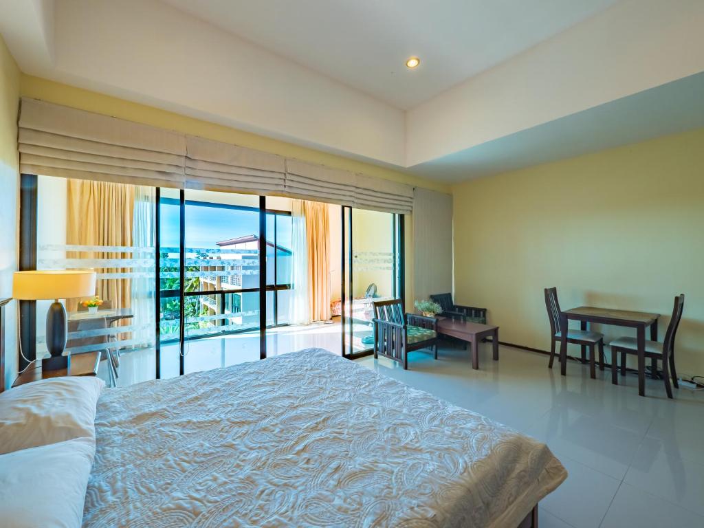 a bedroom with a bed and a table and a balcony at Condo AVANTA Unit А405 in Ban Tai