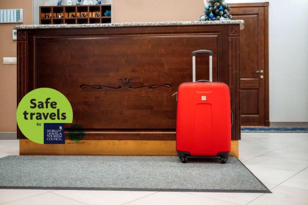 a red suitcase sitting in front of a wall at Boutique Hotel North Flower in Saint Petersburg