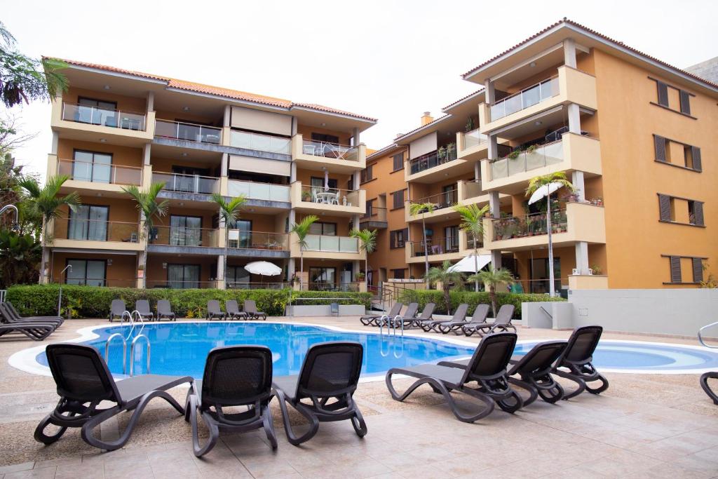 una piscina con sillas y un edificio en Sweet Home Puerto de la Cruz, en Puerto de la Cruz