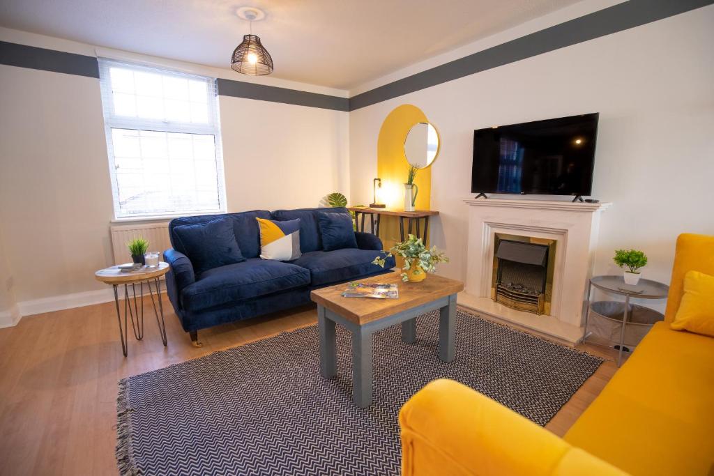 a living room with a blue couch and a fireplace at Saltbox Properties- LARGE!! 3 bed, 3 bath house, parking, fast wifi, town centre location! sleeps 6 in Ashby de la Zouch