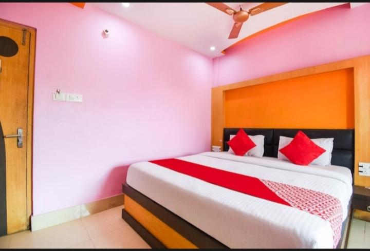 um quarto com uma cama grande e almofadas vermelhas em Hotel Galaxy Inn em Calcutá