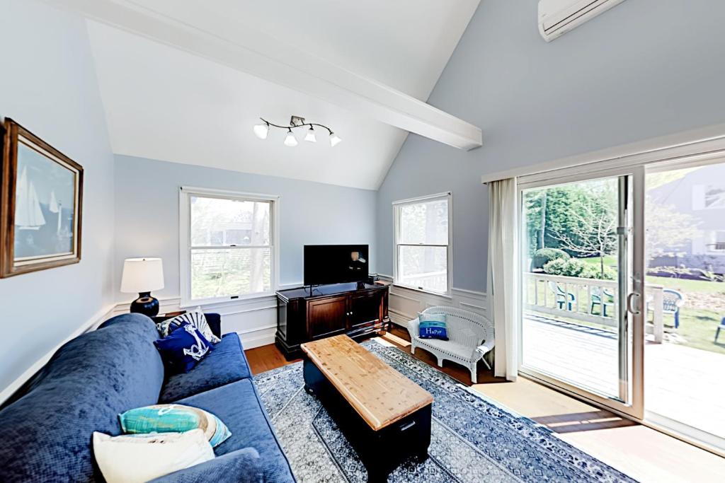 uma sala de estar com um sofá azul e uma televisão em Ferry Harbor Cottage em Falmouth