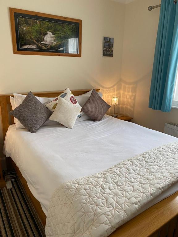 1 dormitorio con cama blanca y almohadas en Four Seasons Guest House, en Canterbury