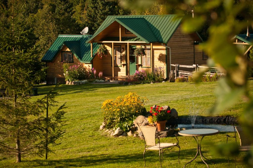 una casa con una mesa y sillas frente a ella en Chalet Paradis de Charlevoix, en Baie-Saint-Paul