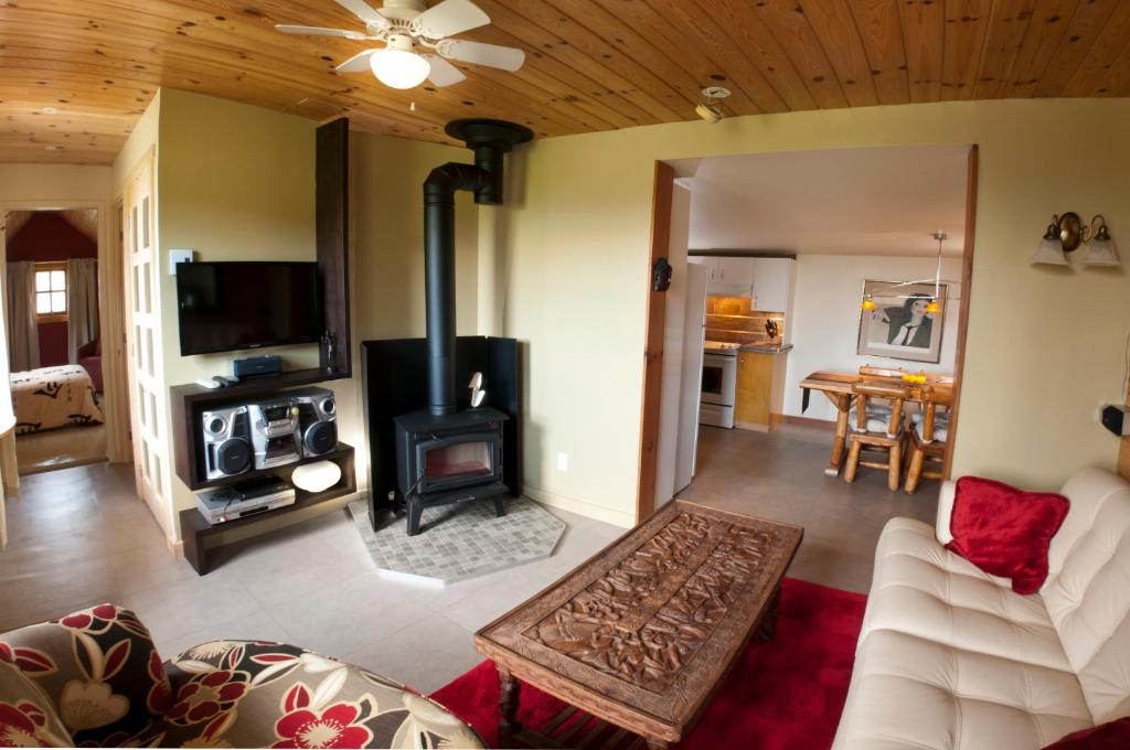 a living room with a fireplace and a stove at Chalet Paradis de Charlevoix in Baie-Saint-Paul