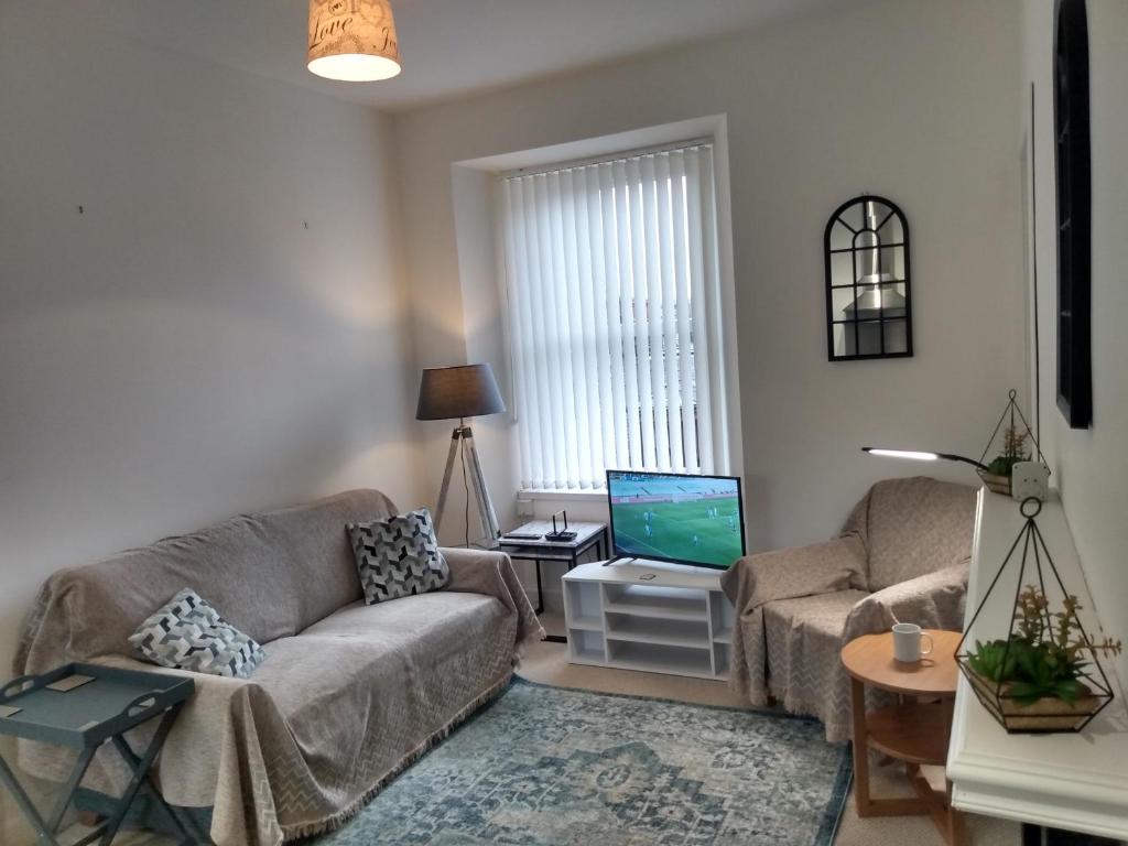 ein Wohnzimmer mit einem Sofa und einem TV in der Unterkunft Rosevale Apartment in Hawick
