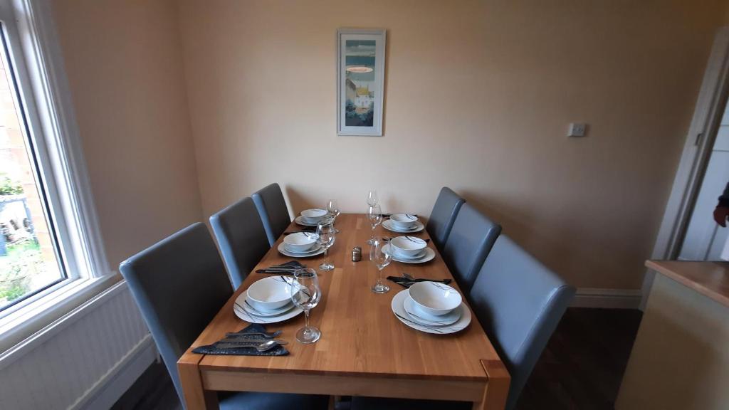 a wooden table with chairs and plates on it at "Near to the Beach "- 2 bedroom Flat Sleeps up to 5 in Burnham on Sea