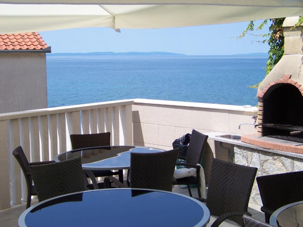 a patio with tables and chairs and an outdoor fireplace at Apartments Bozikovic in Podstrana