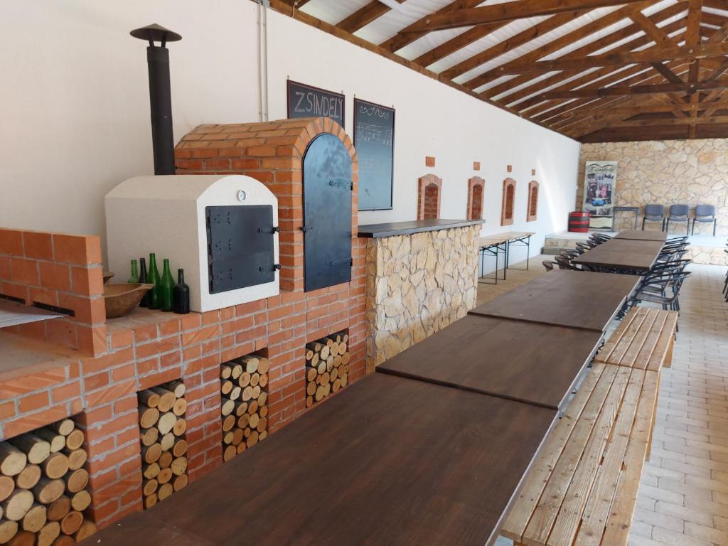 a row of tables in a room with a brick fireplace at Zsindely Ház Károlyfalva Sátoraljaújhely in Sátoraljaújhely