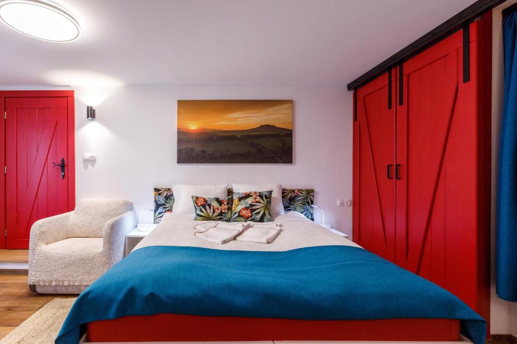 um quarto com armários vermelhos, uma cama e uma cadeira em Origo Vendégház em Hévíz