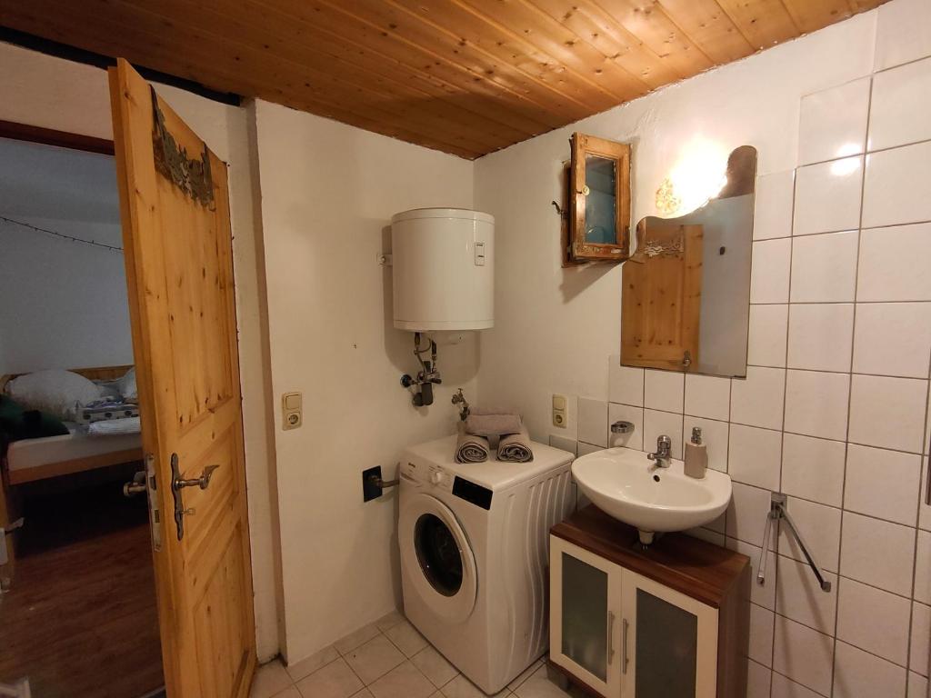 ein kleines Badezimmer mit Waschmaschine und Waschbecken in der Unterkunft Gemütliche Ferienwohnung mit Kamin und Garten in Garmisch-Partenkirchen