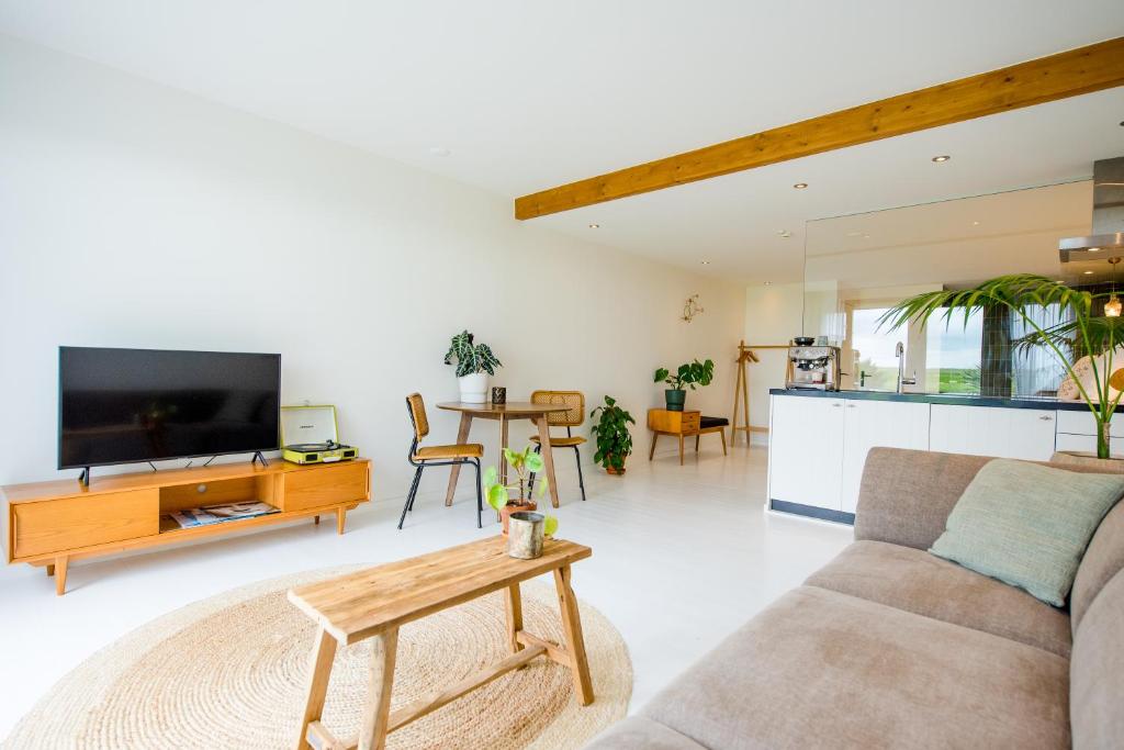 a living room with a couch and a tv and a table at The Sunset Apartments in Hollum