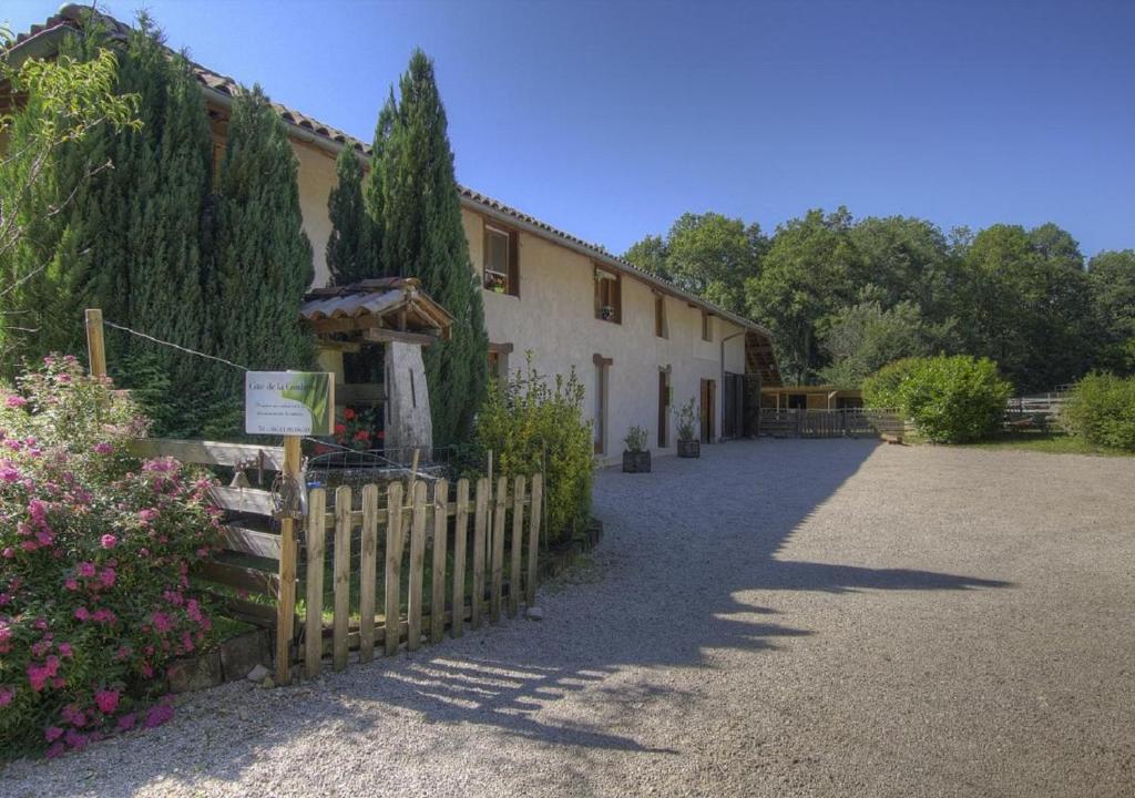 un bâtiment avec une clôture et des fleurs devant lui dans l'établissement le paradis vert, à Pirajoux