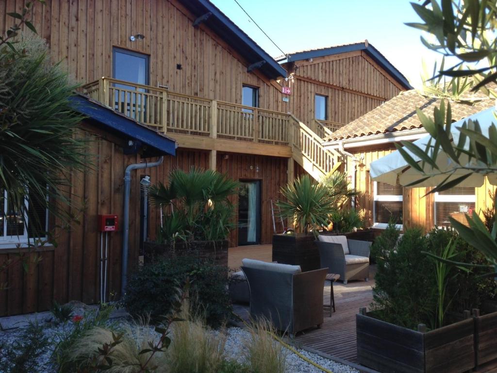 un edificio con una terraza con sillas y plantas en Hotel du Cap, en Cap-Ferret