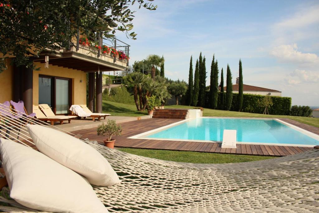 a swimming pool with a hammock and a house at B&B Belvedere in Castiglione delle Stiviere