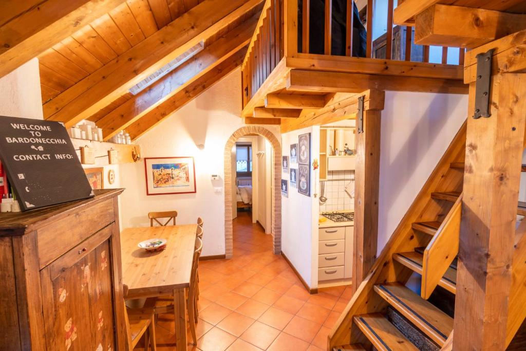 una cucina e una sala da pranzo con scale in legno in una casa di Pochi passi dalle piste di Les Arnaud a Bardonecchia