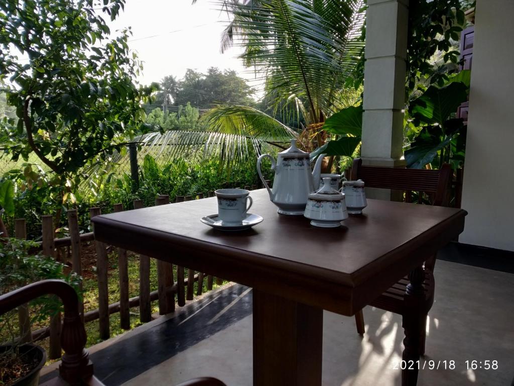 a wooden table with cups and tea pots on a balcony at Guruwaththa Eco Lodge in Hikkaduwa