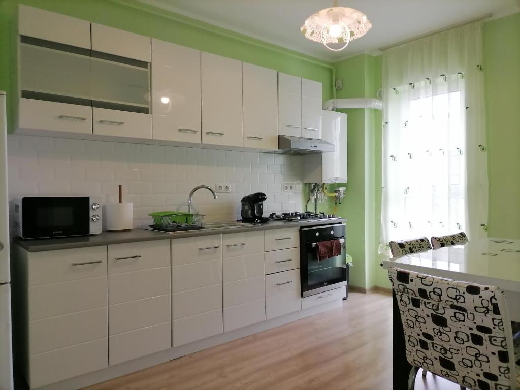 a kitchen with white cabinets and a stove top oven at Apartament NyX in Floreşti